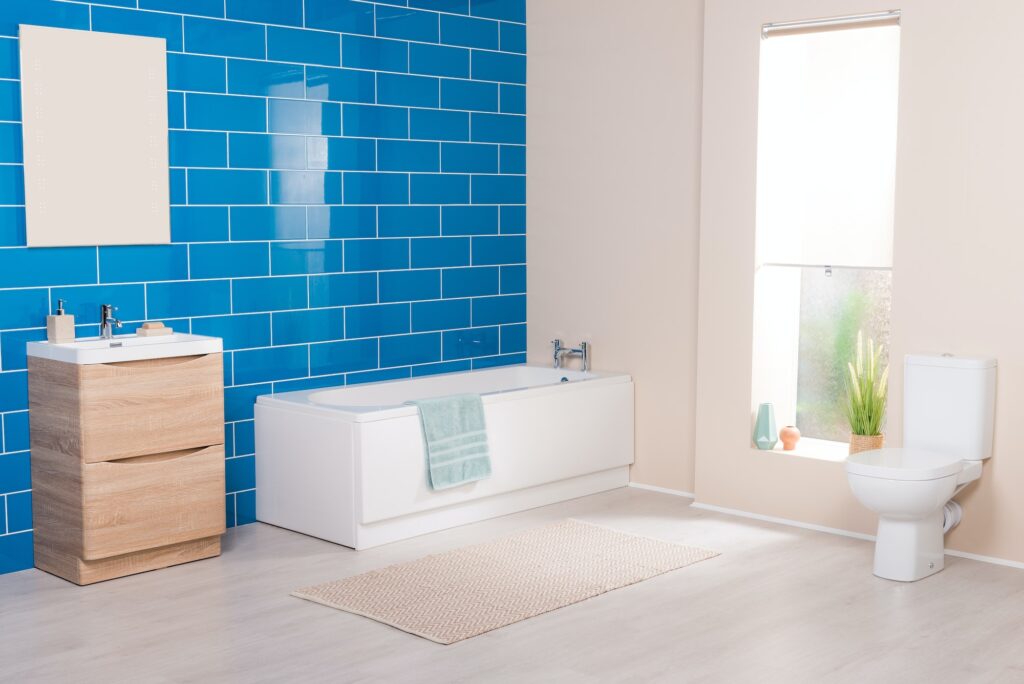 Beautiful shot of a bright bathroom with blue brick wall, bathtub, cabinet and toilet