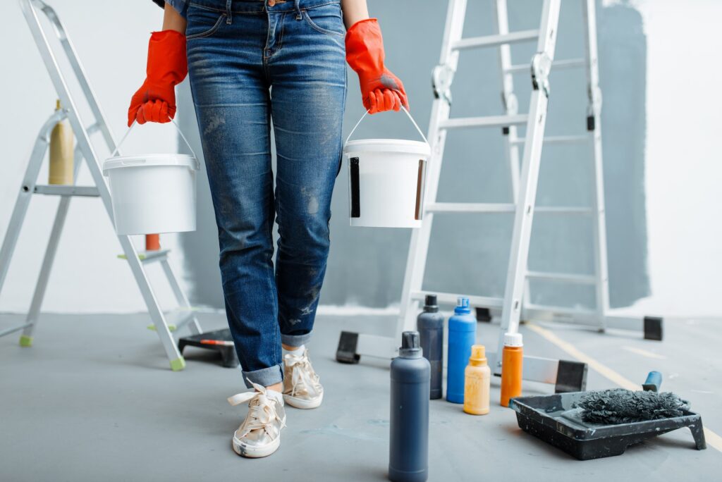 Female house painter holds pails with paints