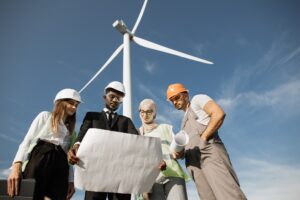 Four partners in helmets studying wind turbine blueprints