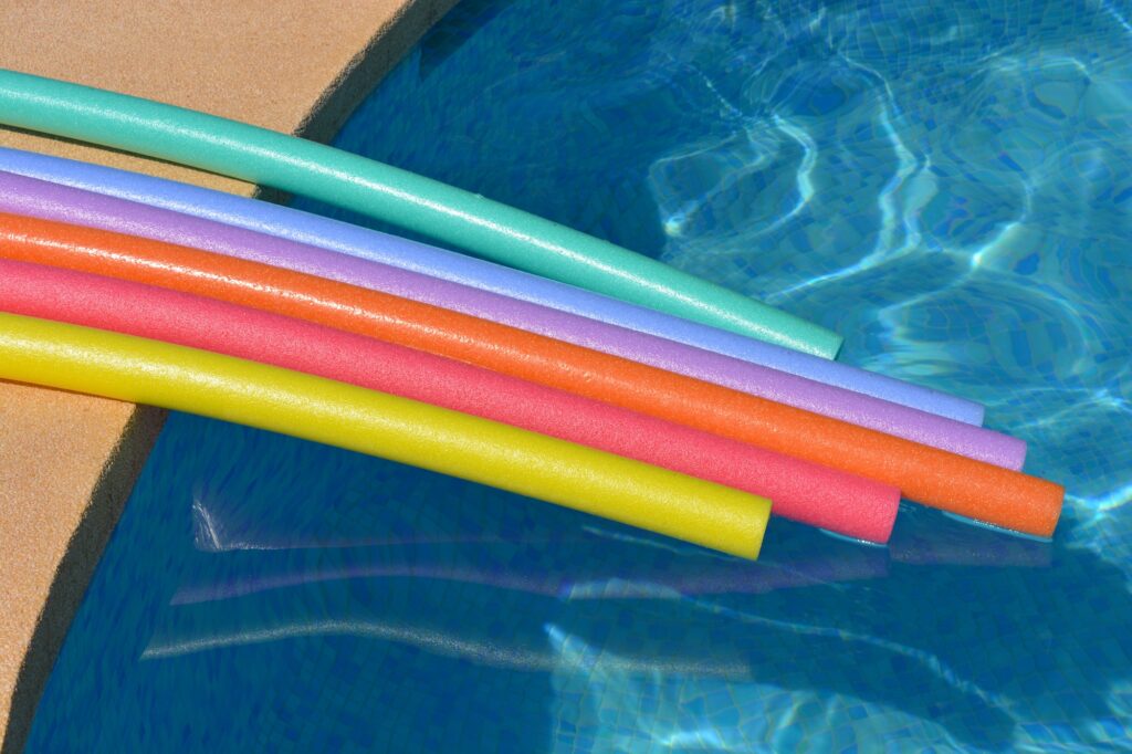 Rainbow pool noodles at poolside in summer