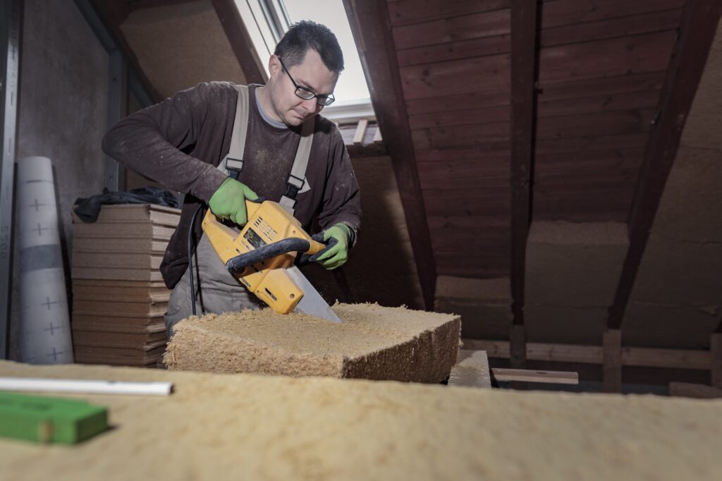 Roof insulation, worker placing wood fibre insulation at the roof