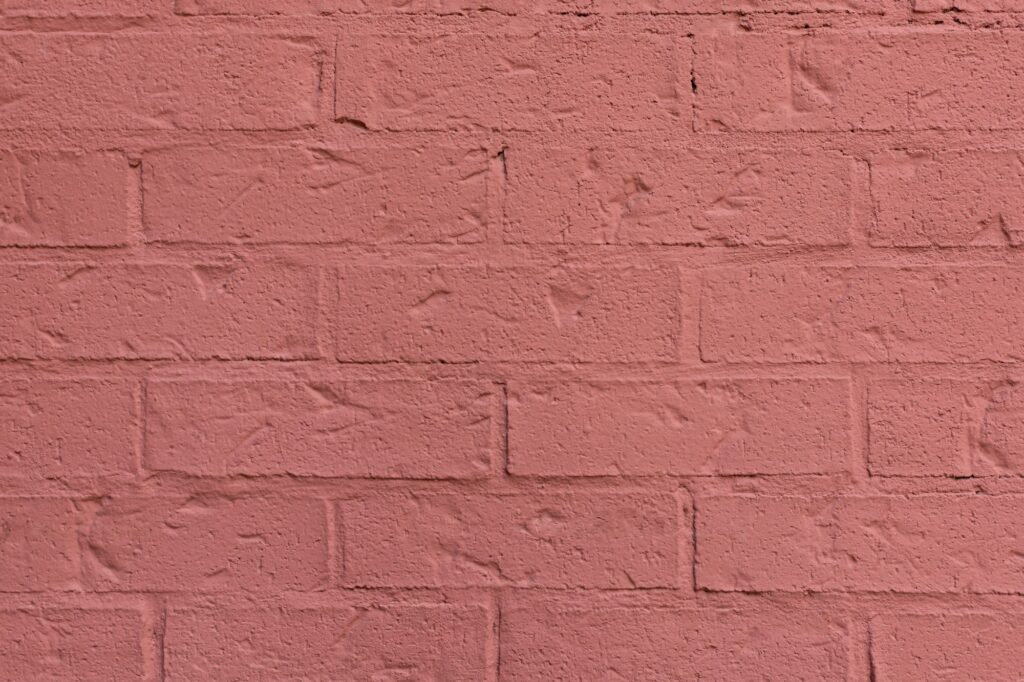 Terracotta brick painted wall textured background close-up.